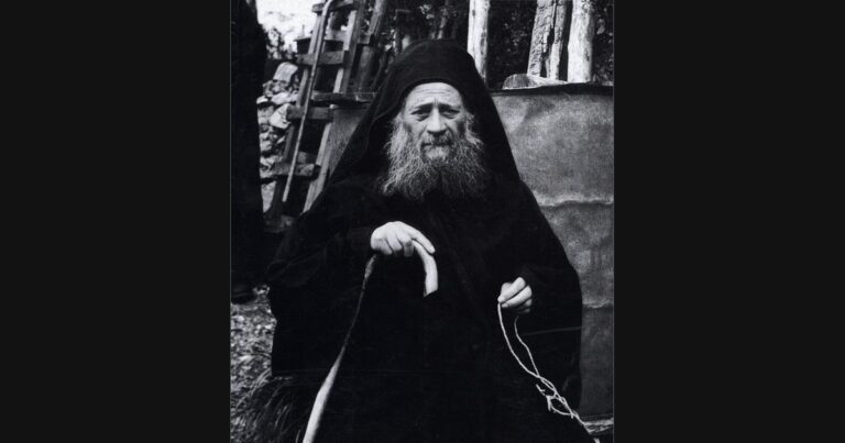 Saint Joseph the Hesychast seated at his Athonite cell with a staff and prayer rope